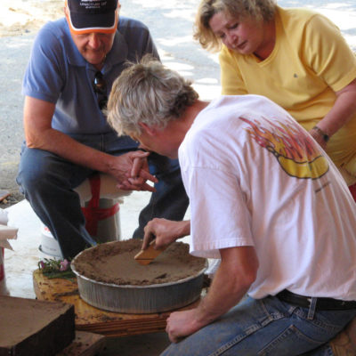 Artist working on mold while two people spectate