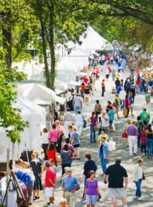 Visitors take a stroll in a row of vendor tents at the Festival of Fine Craft.