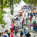 Visitors take a stroll in a row of vendor tents at the Festival of Fine Craft.