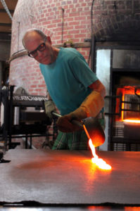 Rob Wynne pouring molten glass on steel table