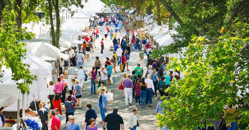 Visitors take a stroll in a row of vendor tents at the Festival of Fine Craft.