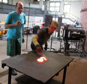 Rob Wynne and apprentice cutting molten glass piece