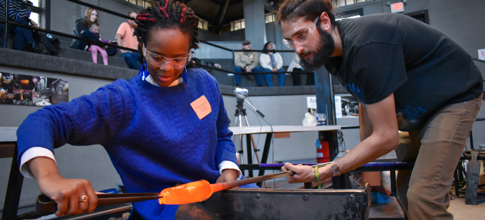 US veteran woman creating a glass object on the Glass Studio floor with glass artist Max.