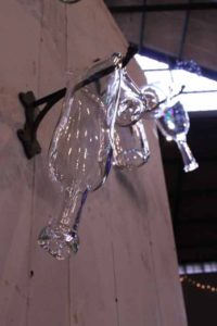 Glass sculptures by Donald Lipski of glass bottles draped like scarves over hanging hooks