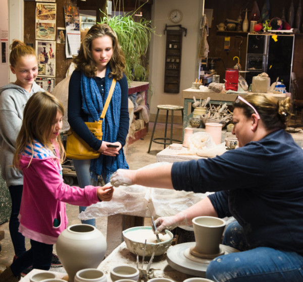 Ceramic artist Phyllis Seidner hands a piece of clay to a child during a demonstration.
