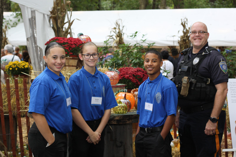 Three volunteers and a police officer at the Glass Pumpkin Patch during the Festival of Fine Craft at WheatonArts