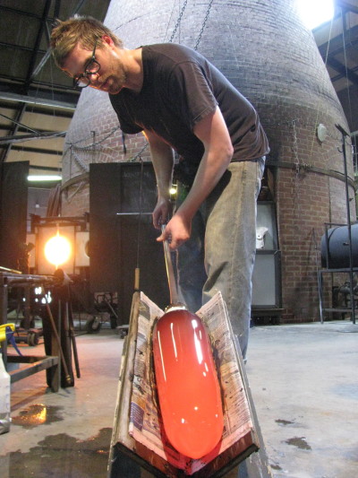 Artist at WheatonArts working on glass piece