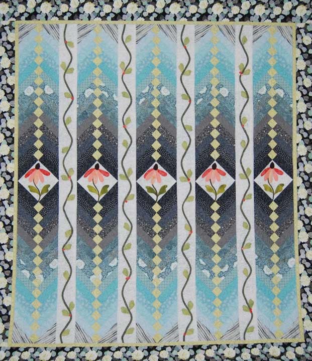 Quilt with patches creating green to dark blue gradient stripes with pink flower centers and a floral border.