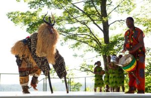 Man playing drum while someone in goat costume dances