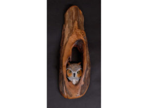 A wooden Sculpture of an owl in a tree by Tom Ahern.