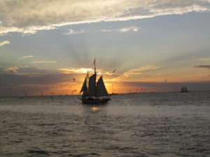 sun setting over a sailboat