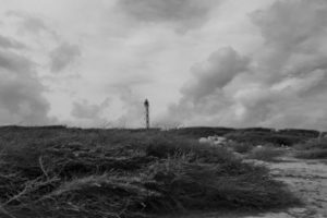 Lighthouse in distance Photograph by Joseph Perno