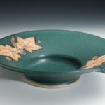 Deep teal plate with detailed tan leaf designs on the lip. Created by Amy Peseller