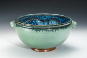 Teal bowl with a green ring around the rim and an orange foot. The inside is a deep cobalt blue. Created by Amy Peseller.