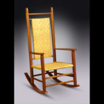 A wooden rocking chair with a yellow back and seat by Douglas Starry