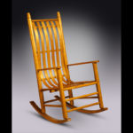 A tan wooden rocking chair with an s-shaped back by Douglas Starry