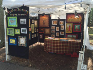 A booth for Painted Stitches: Original Fiber Art, featuring the work of artist Donna Stufft