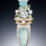 A long silver and gold pendant by Willie Trejbal with several faceted white, blue and green stones stacked over two curved bars and a teal oval stone at the base.