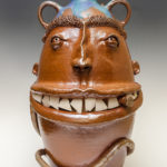 A tall ceramic face jug with a wide mouth by Phyllis Seider