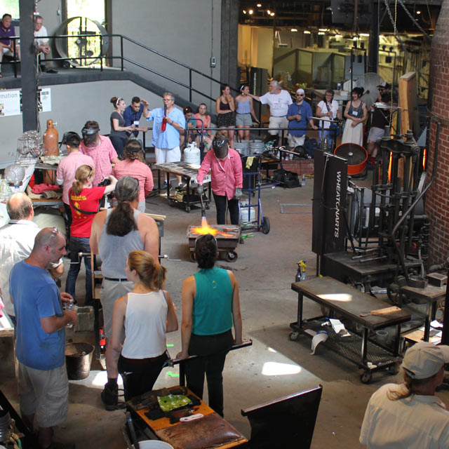 Crowd gathered around a narrated glassblowing demonstration