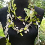 Scarf by Julie Bradley made up of leather cut to resemble leafy vines. A leather luna moth is fashioned as a decoration