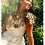 A person leans back in an elegant white dress, looking to the sky. Leather with a cut honeycomb pattern created by Julie Bradley drapes over the model's shoulders and dress