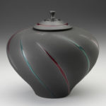 A large lidded grey jar with a wide top, tapering like a funnel to a smaller base. Single curves of alternating green and red go around the piece from bottom to top. Created by Michael Cho