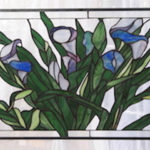 Stained glass panel of deep blue flowers and their rich green leaves by Dennis Christie
