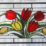 Stained glass panel of bright red and yellow flowers and their leaves by Dennis Christie