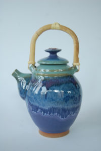 A rich navy teapot with a tan handle and tan foot. Created by Marsha Dowshen