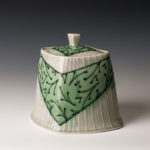 A white ceramic piece with a deep green v wrapped around the center. Created by Lana Heckendorn