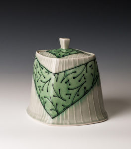 A white ceramic piece with a deep green v wrapped around the center. Created by Lana Heckendorn