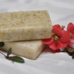 Two bars of soap stacked catercorner with a delicate red flower wrapped around