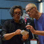 Michael Joo on left and Hank Adams on right, inspecting a piece of glass in Michael's hands