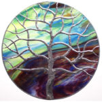 Tree of life motif over green and purple colored glass. Created by Sally Warner.