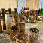Whimsical metal garden sculptures by Sandra Webberking, each formed into a cylinder with images cut around the sides.