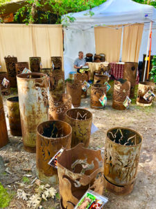 Whimsical metal garden sculptures by Sandra Webberking, each formed into a cylinder with images cut around the sides.