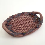 A ceramic piece in the style of a realistic deep brown basket with leaf decorations created by Susan Wechsler