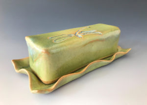 A long yellow green ceramic bar with a dragonfly motif by Deborah Williams