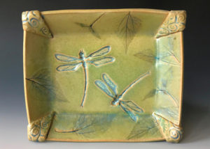 A yellow green plate created by Deborah Williams depicting two dragonflies and several leaves