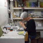 Artist Emily Brown applying enamel to glass cylinder