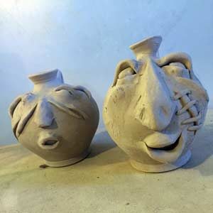 two unfired ceramic face jugs
