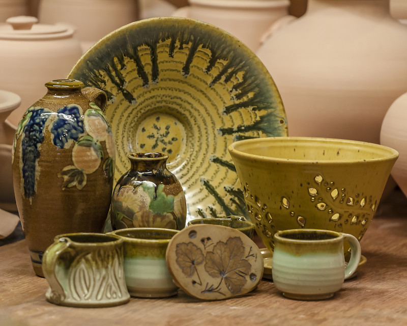 An assortment of earth-toned pottery including vases, mugs, and bowls. Created by Terry Plasket.