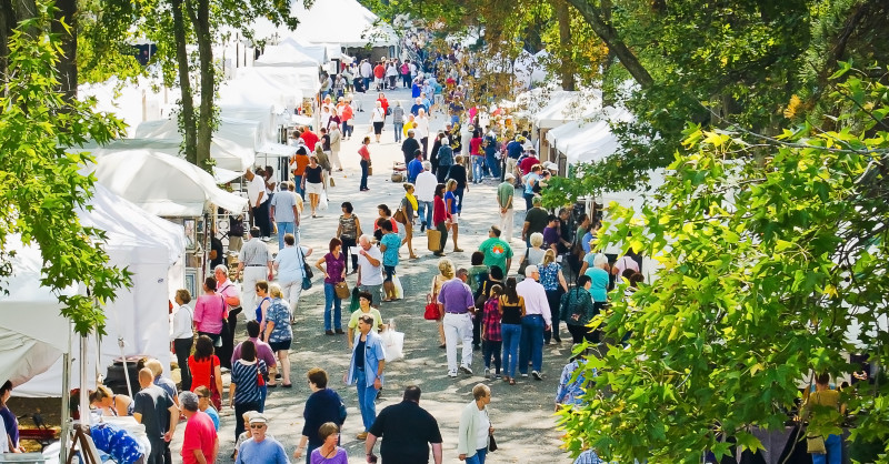 Visitors take a stroll in a row of vendor tents at the Festival of Fine Craft.