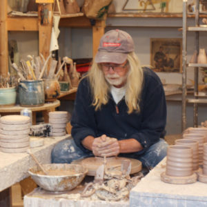 Terry Plasket concentrates on making something out of clay at the potter's wheel