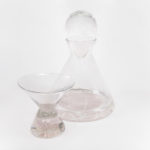 Clear glass decanter and a small glass, both with a slight rose tint. By Skitch Manion