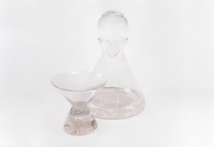 Clear glass decanter and a small glass, both with a slight rose tint. By Skitch Manion