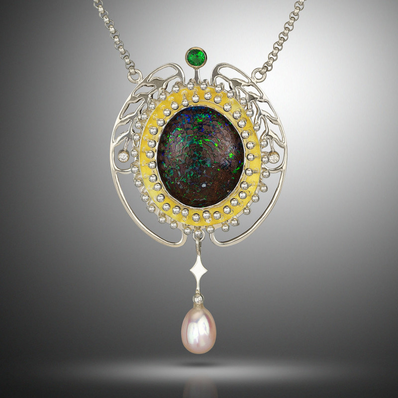 Necklace with a gemstone on an oval between two silver feathers with dangling pearlescent charm. Created by Samantha Freeman.