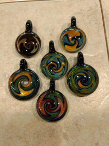 six glass pendants with swirling orange, green, and blue colors by Bill Futer