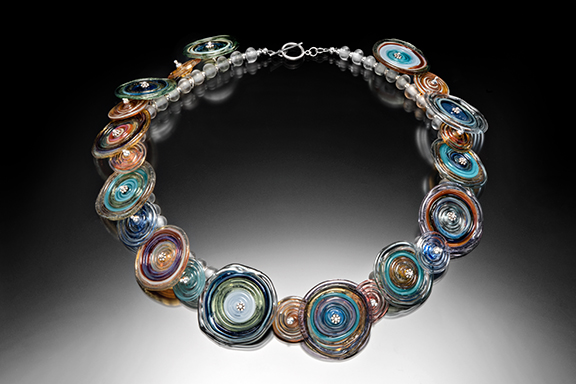 Necklace decorated with multicolored glass spiraled discs with silver balls in the center. Created by Jessica Keemer.